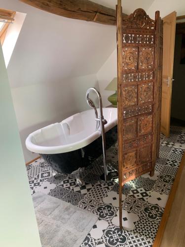La salle de bains est pourvue d'une baignoire et d'un sol noir et blanc. dans l'établissement Le relais de poste Valero, à Serazereux