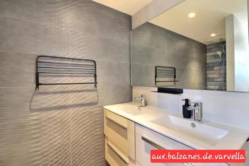 een badkamer met een wastafel en een spiegel bij Piscine intérieure privée chauffée spa toute lannee disponible minimum 2 nuits in Ploudaniel