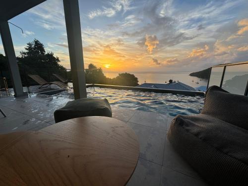 a pool with a table and a sunset in the background at CAP KARAIB Grande Villa in Les Anses-dʼArlets