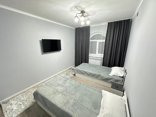 a bedroom with two beds and a flat screen tv at Shetel in Kapchagay