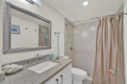 a bathroom with a sink and a toilet and a mirror at Bahia Mar-Solare Tower, Beachfront Resort with Two Pools in South Padre Island