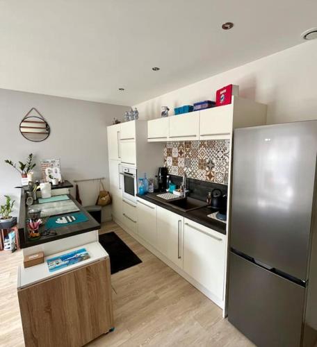 une cuisine avec des armoires blanches et un réfrigérateur en acier inoxydable dans l'établissement Charmant appartement à Roanne, à Roanne