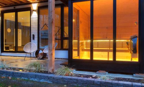 a house with glass windows and a chair on a patio at Chalet Peak Tremblant: Your Mountain Escape. in La Conception