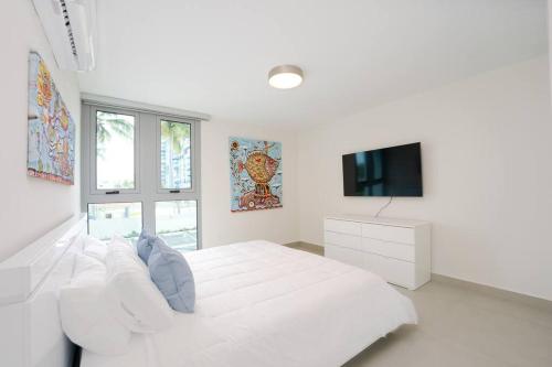 a white bedroom with a white bed and a tv at Luxury suite at Solemare suite with pool and wifi in San Juan