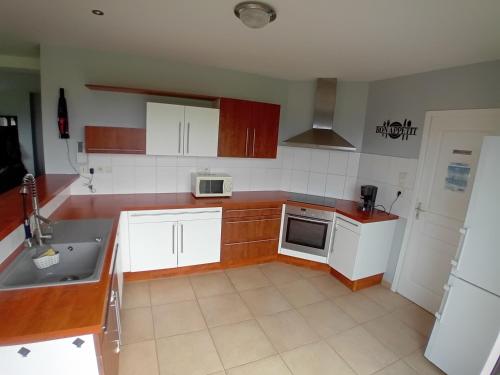 une cuisine avec des armoires blanches et un évier dans l'établissement Gîte du Buron 6 8 personnes, à Longueville