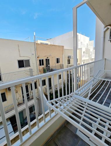 a balcony with white railing and a view of buildings at Seaside 4 in Marsaskala