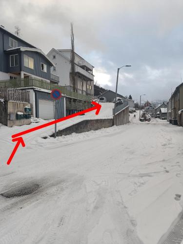 a snowy street with a red arrow on a road at The Garage in Narvik