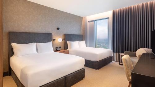 a hotel room with two beds and a window at Hilton Woking in Woking