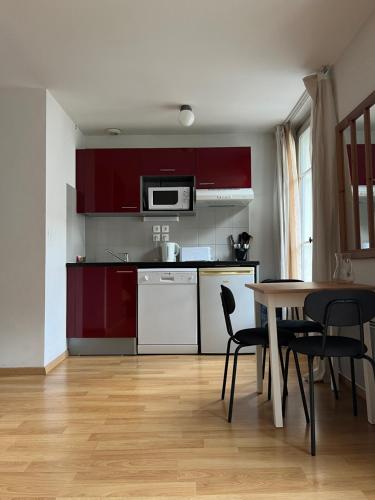 une cuisine avec des armoires rouges et une table et des chaises dans l'établissement Chez Laure et Guilhem, à Luchon