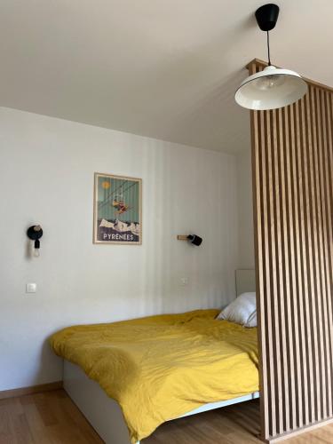 une chambre avec un lit avec une couverture jaune dans l'établissement Chez Laure et Guilhem, à Luchon