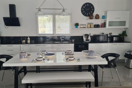 a white kitchen with a table with bowls and chairs at Villa Romana Monastir in Monastir