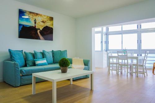 a living room with a blue couch and a table at Apartamento frente al mar in Puertito de Güímar