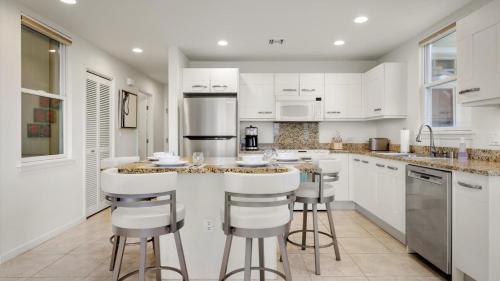 a kitchen with white cabinets and bar stools at Na Hale H2 in Kailua-Kona