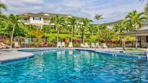 a pool at a resort with chairs and palm trees at Na Hale H2 in Kailua-Kona