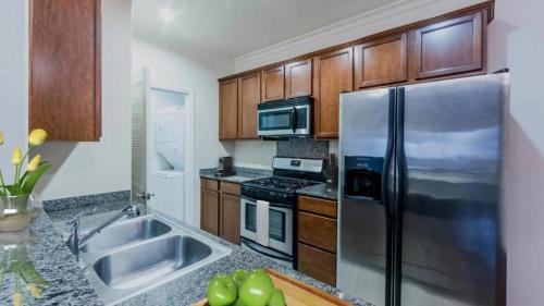 a kitchen with a stainless steel refrigerator and wooden cabinets at Holiday in LA - 1br with Free parking, Laundry, Pool in Los Angeles