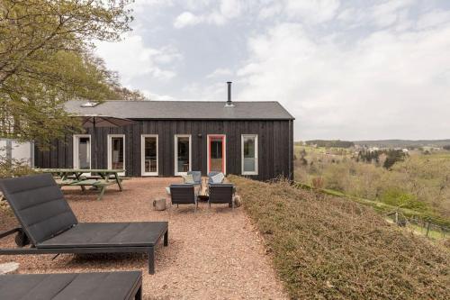 a small black house with chairs and a table at Super view Am Flachsberg in Butgenbach