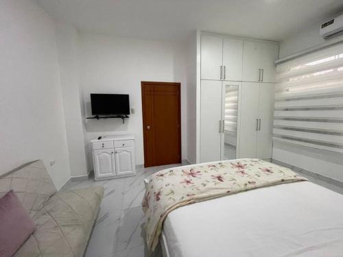 マチャラにあるConfortable Apartamento # 2 planta bajaのベッドとテレビのある白い寝室
