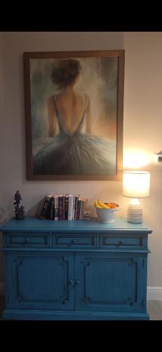 a blue dresser with a painting of a woman at Newly built Villa Ballerina with heated pool and incredible view into beautiful Arrowheadcanal in Cape Coral