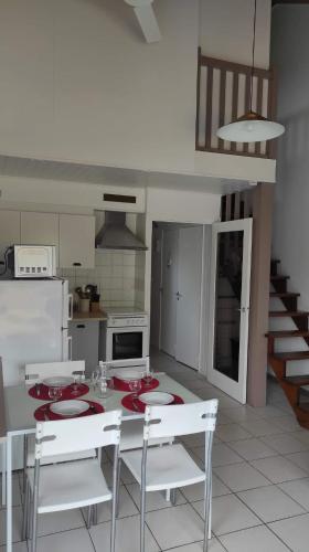 une cuisine avec une table et des plaques et des chaises rouges dans l'établissement Les châlets de Renoir 1, à La Roche-Posay