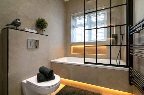 a bathroom with a toilet and a tub and a window at The golden place in London