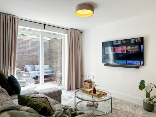 a living room with a couch and a tv on a wall at NEW Edwin Bing Mews -Luxury City Centre Home - FREE Parking in Canterbury