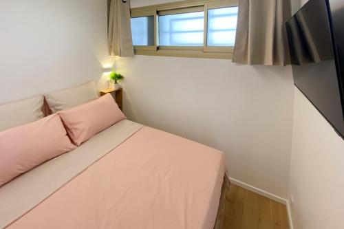 une petite chambre avec un lit rose et une fenêtre dans l'établissement 06K1 - Front of the sea-renovated-terraceparking, à Saint-Laurent-du-Var