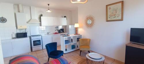 - une cuisine avec des placards blancs et des chaises bleues dans l'établissement Rosemonde- Logement sur le quai de la chaume, à Les Sables-dʼOlonne