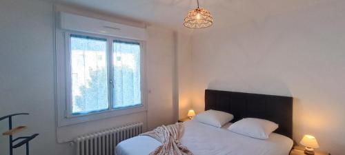 une chambre avec un lit avec des draps blancs et une fenêtre dans l'établissement Rosemonde- Logement sur le quai de la chaume, à Les Sables-dʼOlonne