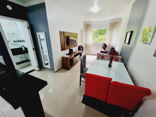 ein Wohnzimmer mit einem weißen Tisch und roten Stühlen in der Unterkunft Edifício Plaza de Saint Martin in Santos