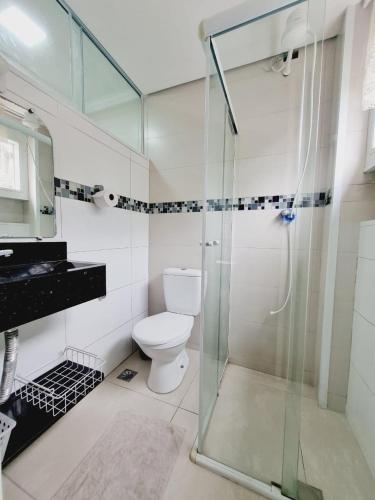 a bathroom with a toilet and a glass shower at Edifício Plaza de Saint Martin in Santos