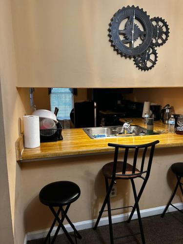 a clock on the wall above a kitchen counter with two stools at #Cozy2BR Near Stonecrest Stone MTN Park in Lithonia