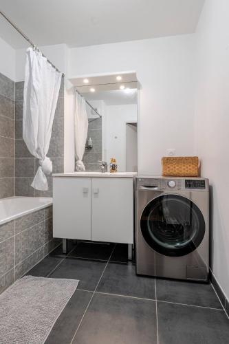 - un lave-linge dans la salle de bains pourvue d'un miroir dans l'établissement l'Éden familial - cosy T3 proche Disneyland avec jardin, à Vaires-sur-Marne