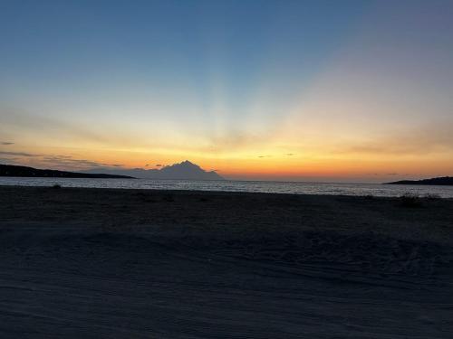 a sunset on the beach with a mountain in the background at Villa Marianna-Nina Holidays in Paralia Sikias