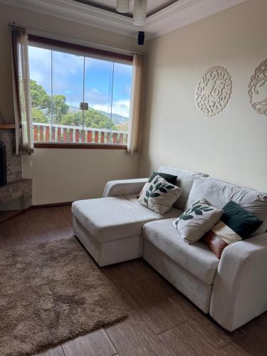 a living room with a white couch and a window at Casa para até 8 pessoas ou studio para até 3 com fácil acesso à pontos turísticos in Campos do Jordão