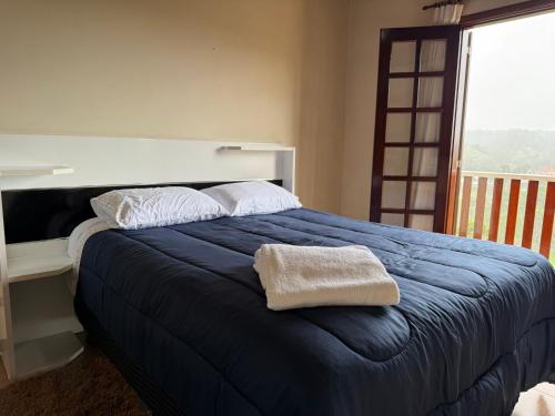 a bedroom with a blue bed and a window at Casa para até 8 pessoas ou studio para até 3 com fácil acesso à pontos turísticos in Campos do Jordão