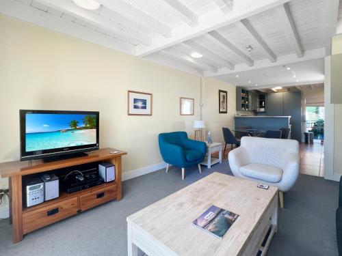 a living room with a television and a table at Waterfront 2-Bedroom Harbour View Apartment in Akaroa