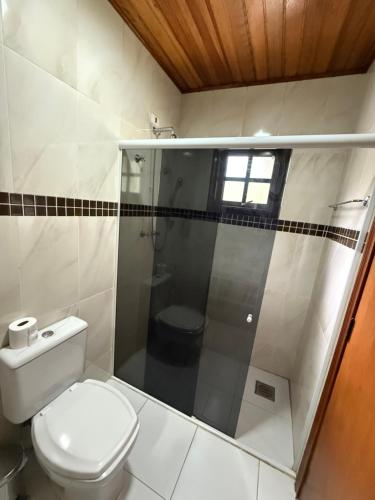 a bathroom with a white toilet and a shower at Casa para até 8 pessoas ou studio para até 3 com fácil acesso à pontos turísticos in Campos do Jordão