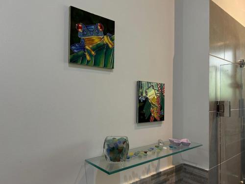 a bathroom with a glass shelf and paintings on the wall at Villa Mariposa - Ojochal, Close To Everything in Ojochal