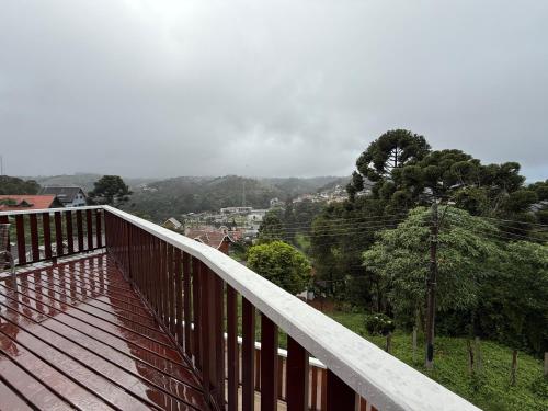 a wooden balcony with a view of a city at Casa para até 8 pessoas ou studio para até 3 com fácil acesso à pontos turísticos in Campos do Jordão