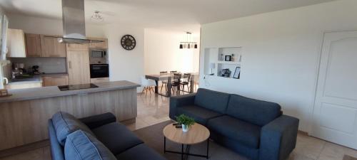 a living room with two blue couches and a kitchen at "Le petit Breizh 2" entre Mt St Michel et Saint Malo 6personnes 1bébé in Saint-Marcan