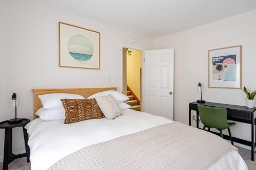 a bedroom with a white bed with a desk and a computer at Beacons Beach Cottage in Encinitas