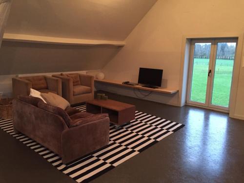 a living room with two couches and a television at Vakantie Appartement De Sneppelhoeve in Wuustwezel