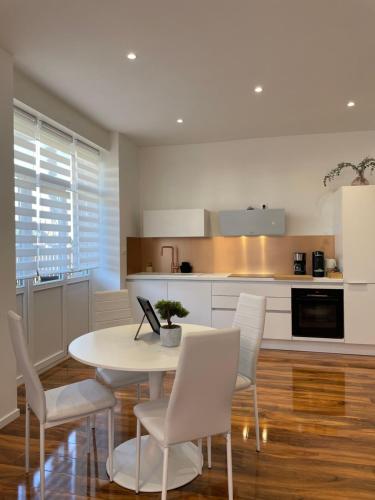 - une cuisine avec une table blanche et des chaises blanches dans l'établissement Le Haut Standing, à Bennwihr