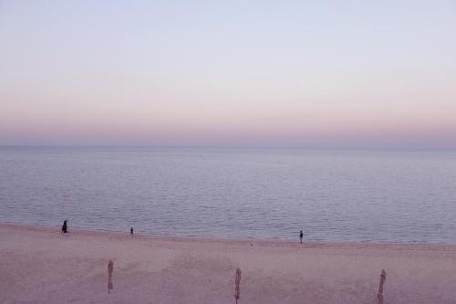 two people standing on a beach near the water at Aquamarine Kuwait Resort(Families Only) in Al Nuwaiseeb