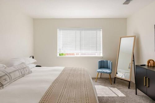 a white bedroom with a mirror and a blue chair at Leucadia's Beach House w Game Room in Encinitas