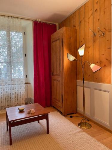 a living room with a table and a lamp at Petit appartement au rez in Baulmes
