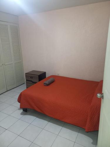 a bedroom with a bed with a red blanket and a dresser at Hotel Económico Morelia in Morelia