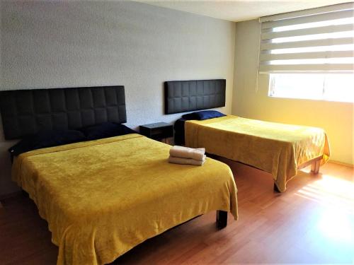 a room with two beds with yellow sheets and a window at Hotel Económico Morelia in Morelia