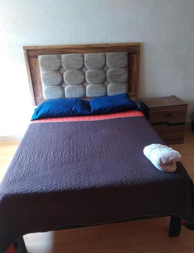 a bedroom with a large bed with blue pillows at Hotel Económico Morelia in Morelia