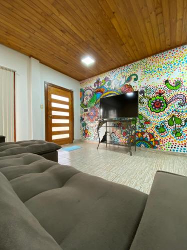 a living room with a tv and a colorful wall at CostaRóga in Encarnación